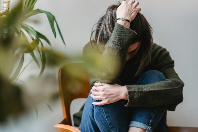 person sitting with arm wrapped around needs and head in hand