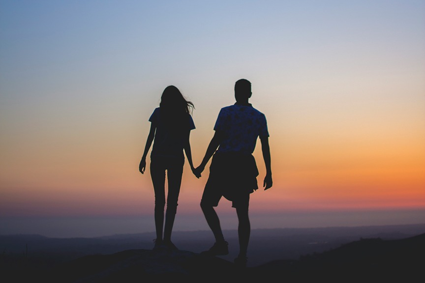 silhouette of two people holding hands during sunset