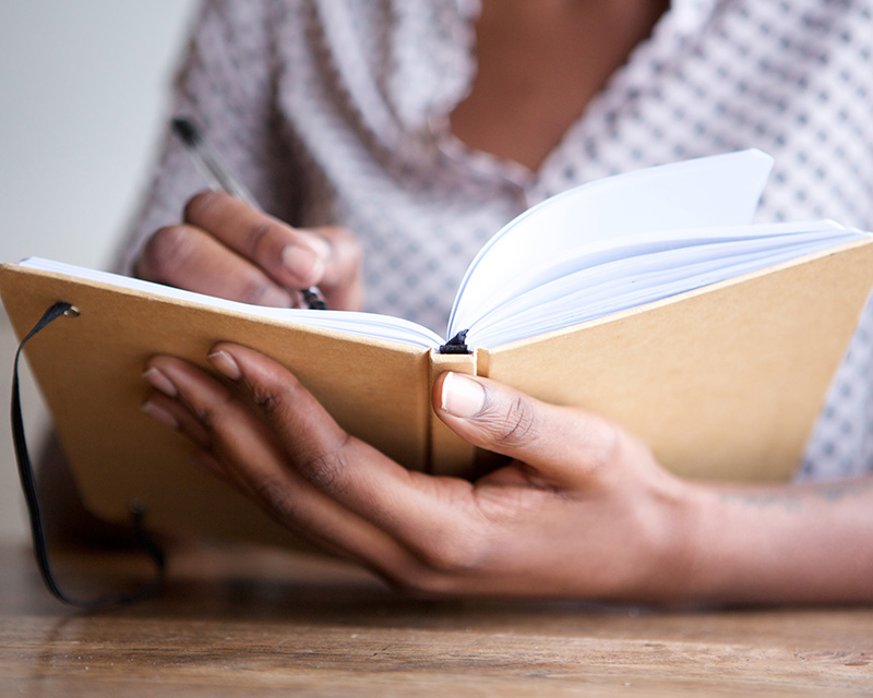 Black woman writing in a journal after Borderline Personality Treatment