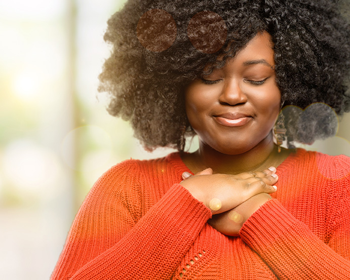 Black woman with hands on her heart, feeling empowered after remote online therapy in New York